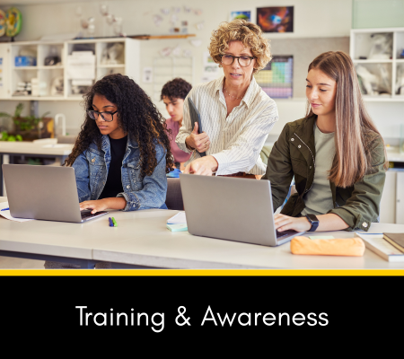 Image of an instructor helping students at a table with laptops, with the words Training and Awareness