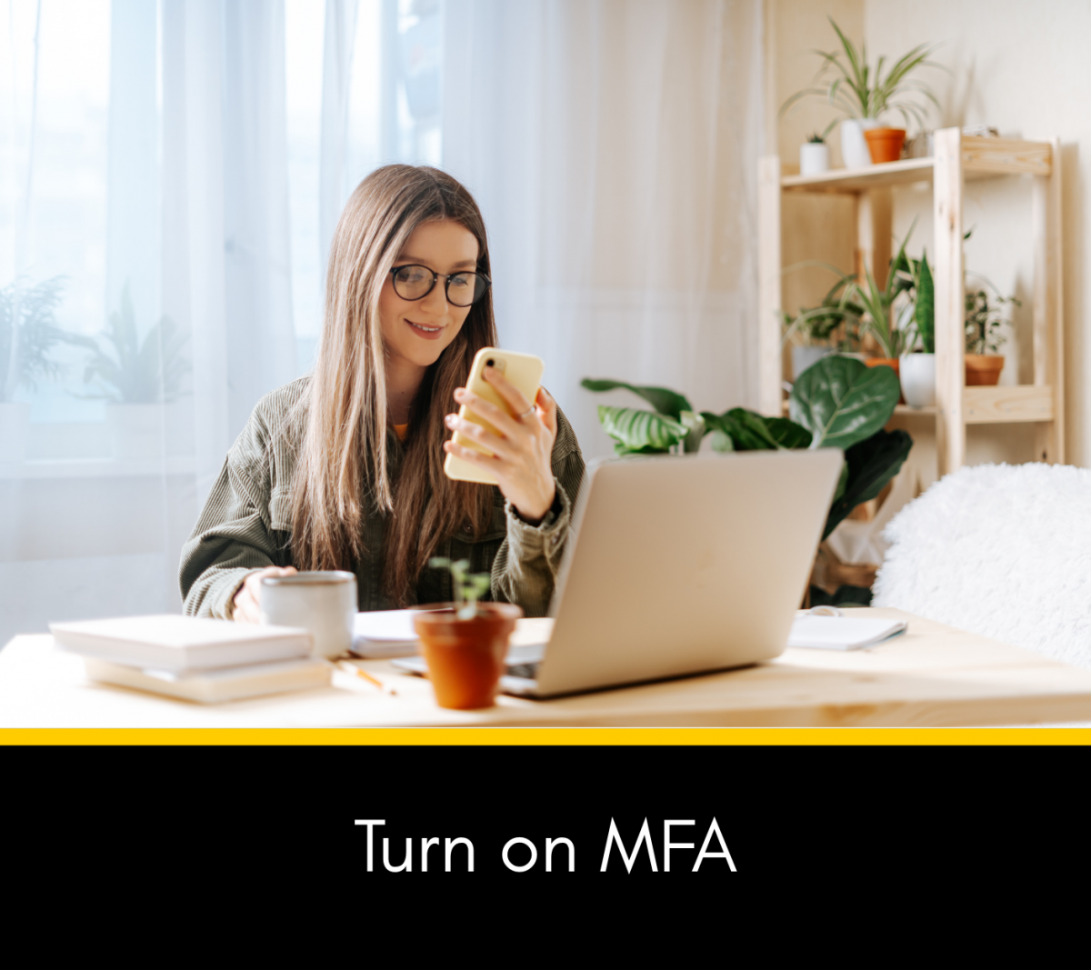 Image of a person turning on their MFA on cellphone while sitting at a laptop with the words Turn on MFA