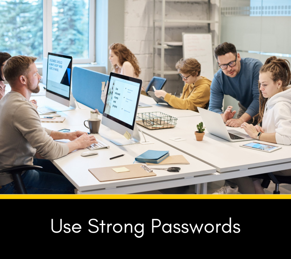 Group of people working at a table with laptops with the words Use Strong Passwords