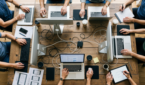 Overhead image of multiple people working at a table on their computers