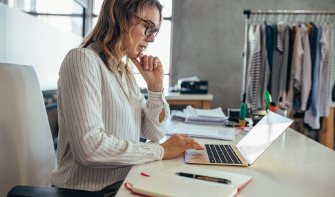 Image of a lady sitting at a desk using a laptop with a concerned look on her face