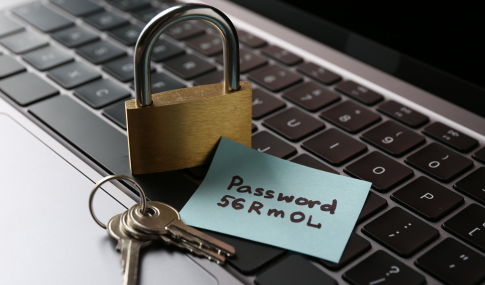 Image of laptop keyboard with a lock, keys, and sticky note with password