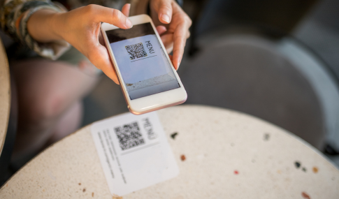 Image of a hand holding a cellphone scanning a QR code