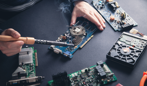 Image of hands holding a soldering device on a computer mother board