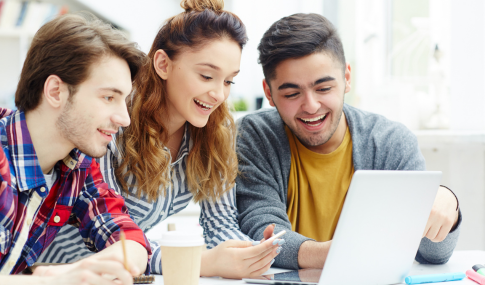 3 people looking at one laptop and smiling at it
