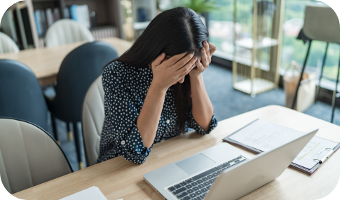 Image of a woman with her head in her hands while sitting in front of a laptop with the words Identity Theft Refund Fraud