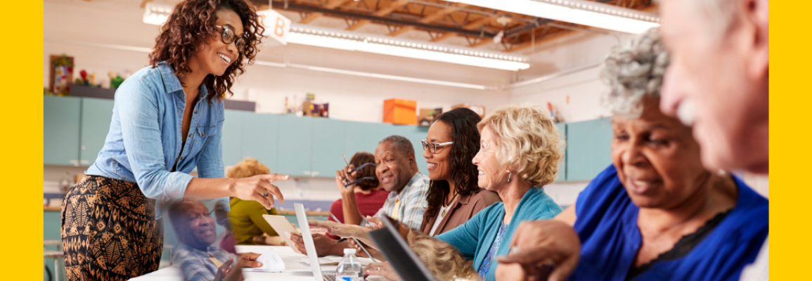 Image of a teacher with adult students using laptops